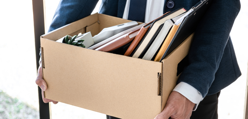 Business professional carrying a box of office supplies and legal documents in Queensland.