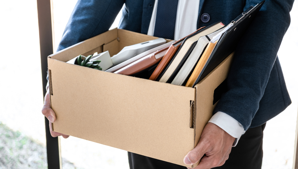Business professional carrying a box of office supplies and legal documents in Queensland.