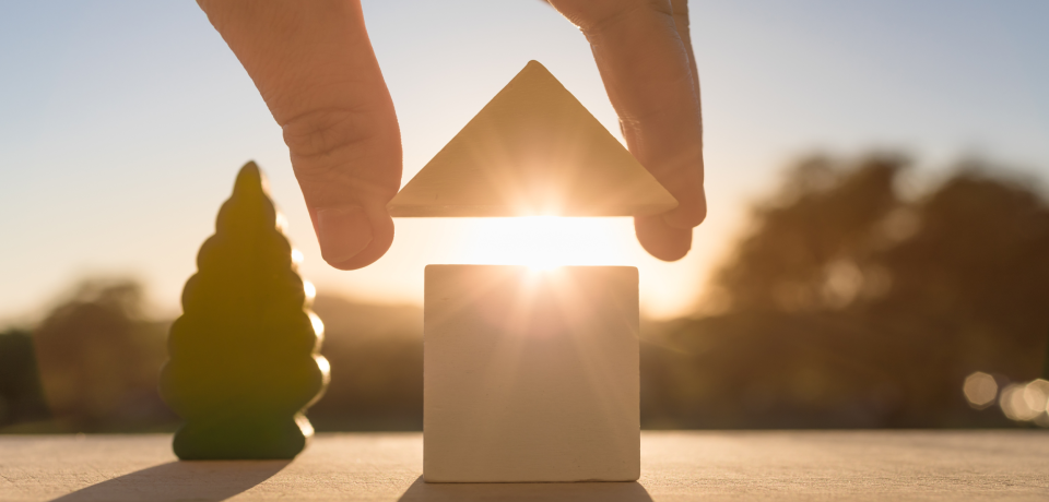 Balanced house of wooden blocks with sunrise, symbolising property law services in Queensland.