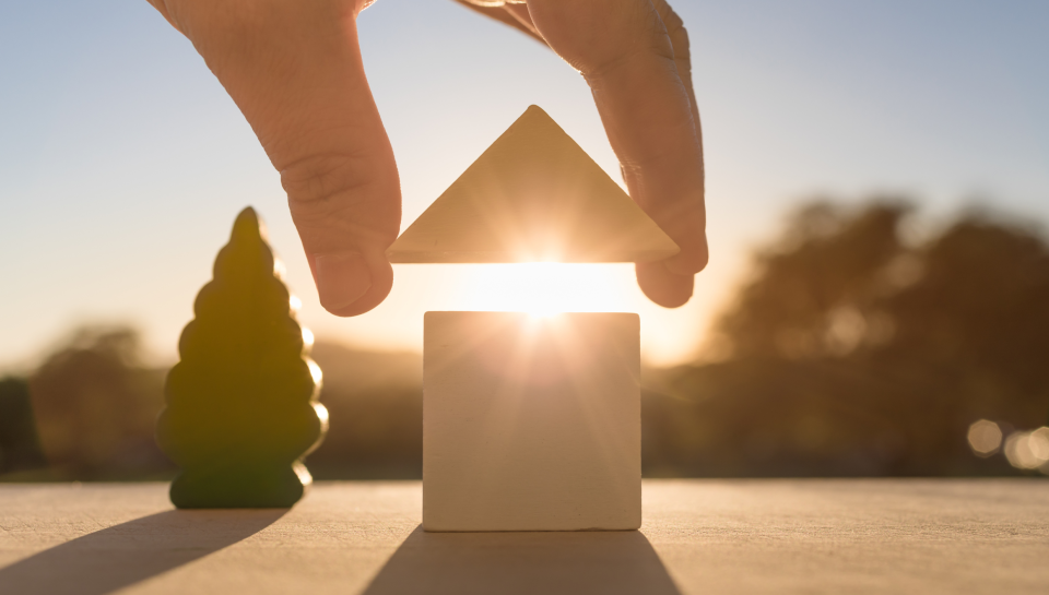 Balanced house of wooden blocks with sunrise, symbolising property law services in Queensland.