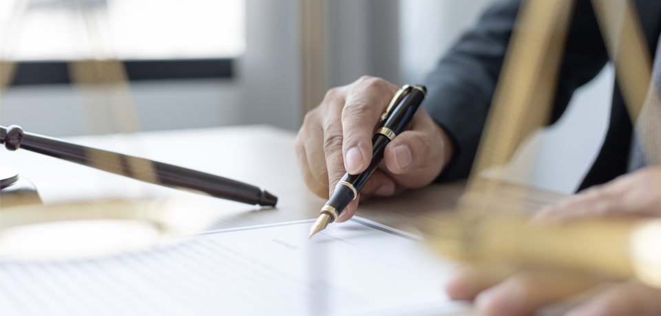 Elegant business lawyer signing contract at office desk.