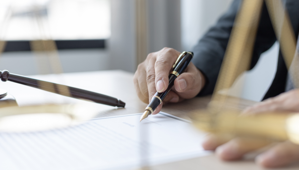 Elegant business lawyer signing contract at office desk.
