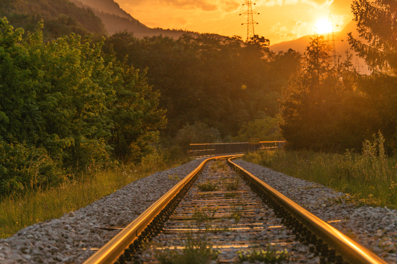 Empty railway tracks during sunset in Toowoomba, Queensland, with surrounding greenery and mountains.