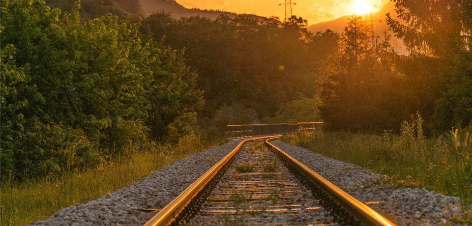 Empty railway tracks during sunset in Toowoomba, Queensland, with surrounding greenery and mountains.