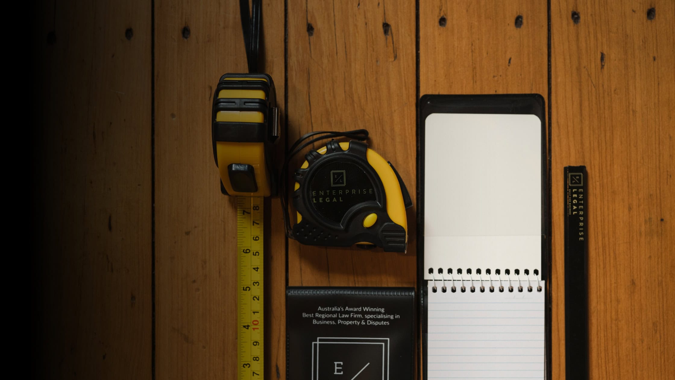 Tape measure, notepad, and ruler on wooden surface used for legal documentation in property and civil dispute cases in Queensland.