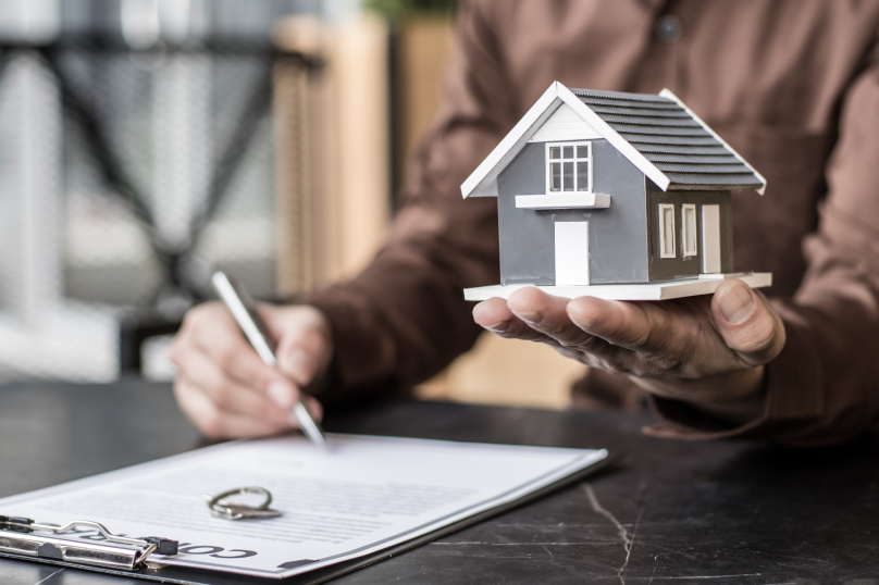Detailed house model held in hand, real estate and property law concept.