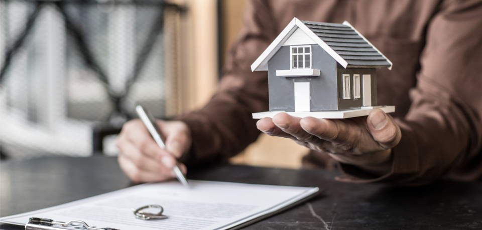 Detailed house model held in hand, real estate and property law concept.