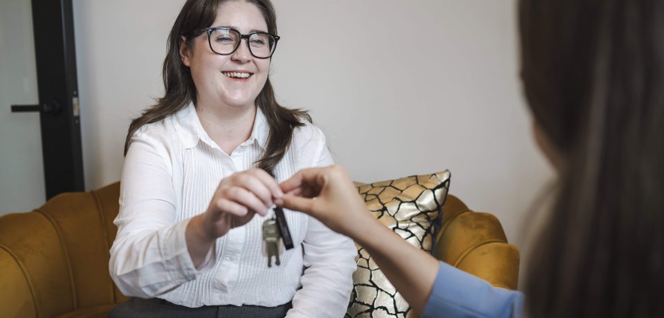 Key handover between woman and real estate agent in property law consultation in Toowoomba.