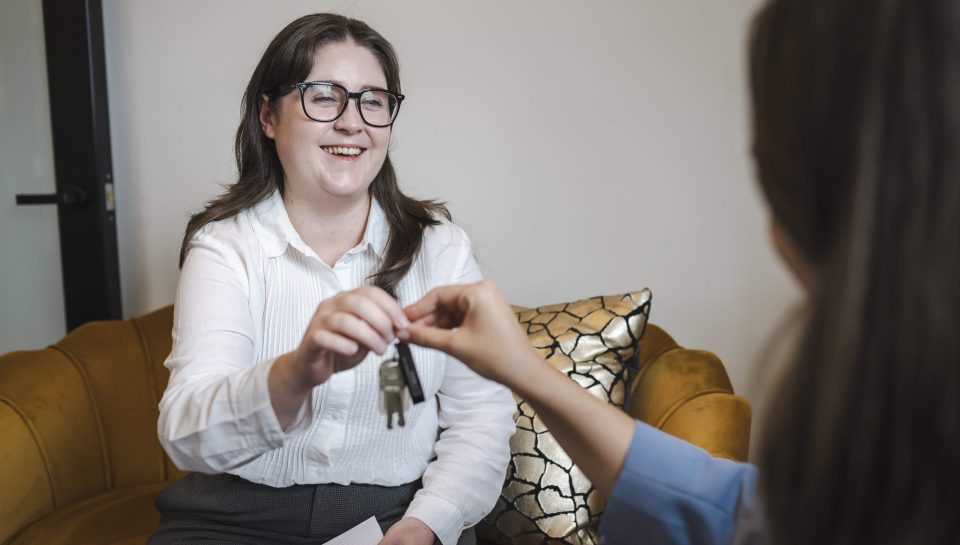 Key handover between woman and real estate agent in property law consultation in Toowoomba.