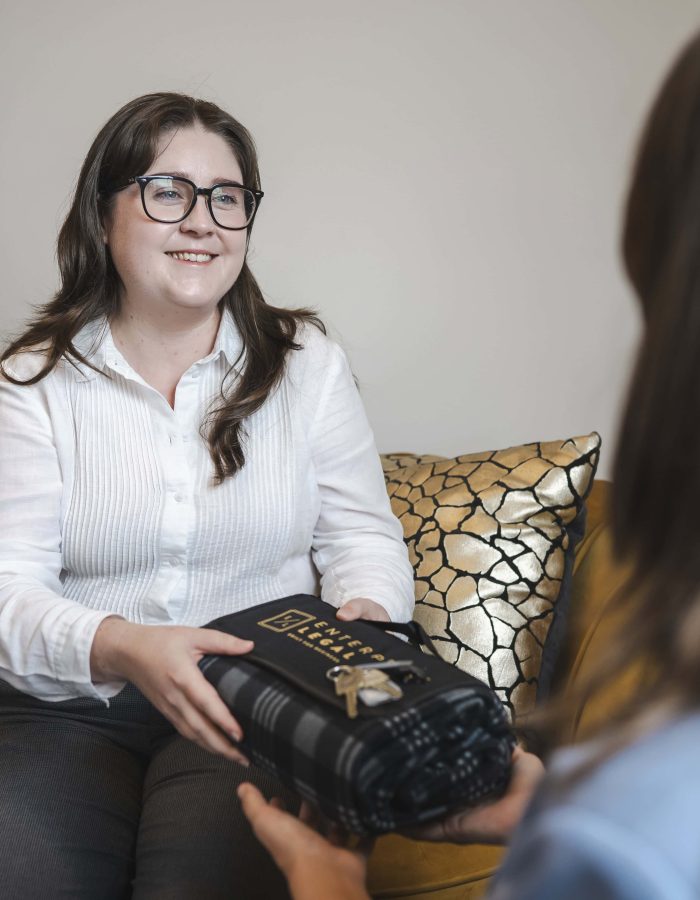 Professional woman handing over legal documents at law firm in Toowoomba, Queensland.