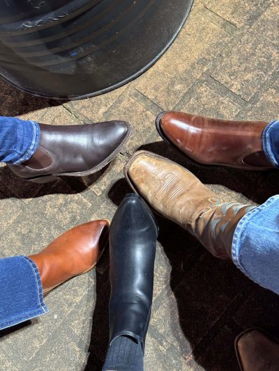 Smart casual shoes and boots in various colours on a brick pavement with a black circular table.