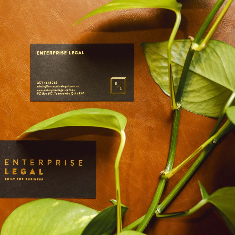 Business law legal business cards with green plant on brown leather background.