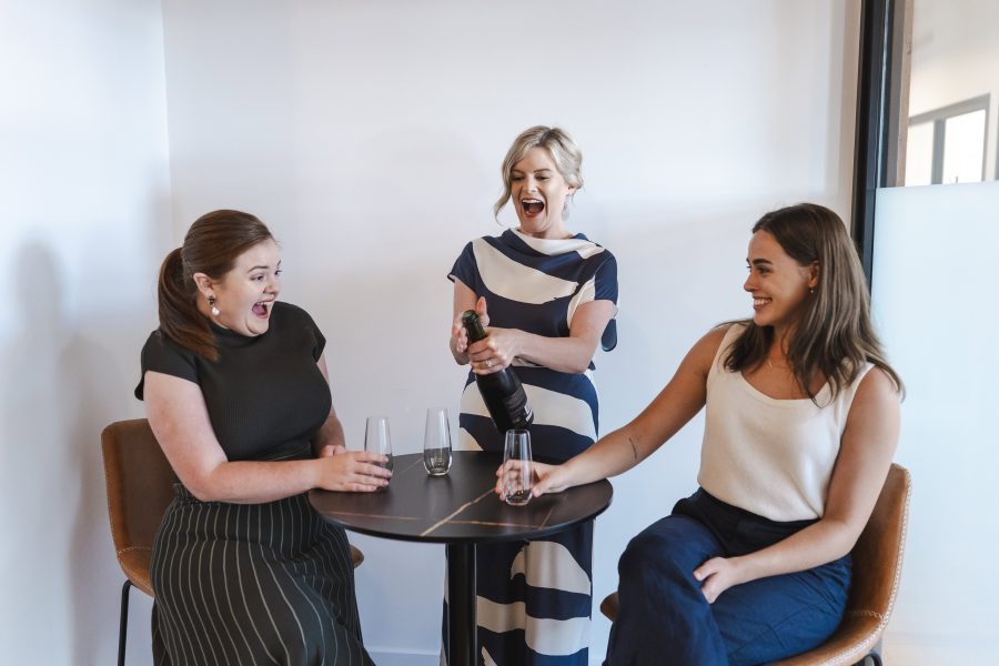 Laughter and celebration among women at a casual gathering in an office setting.