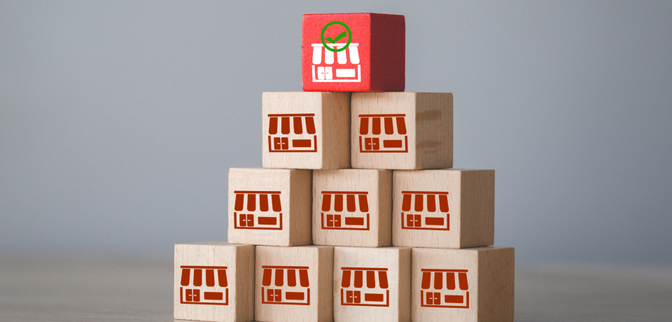 Wooden blocks with store icons stacked in pyramid, representing property law and commercial legal services in Queensland.