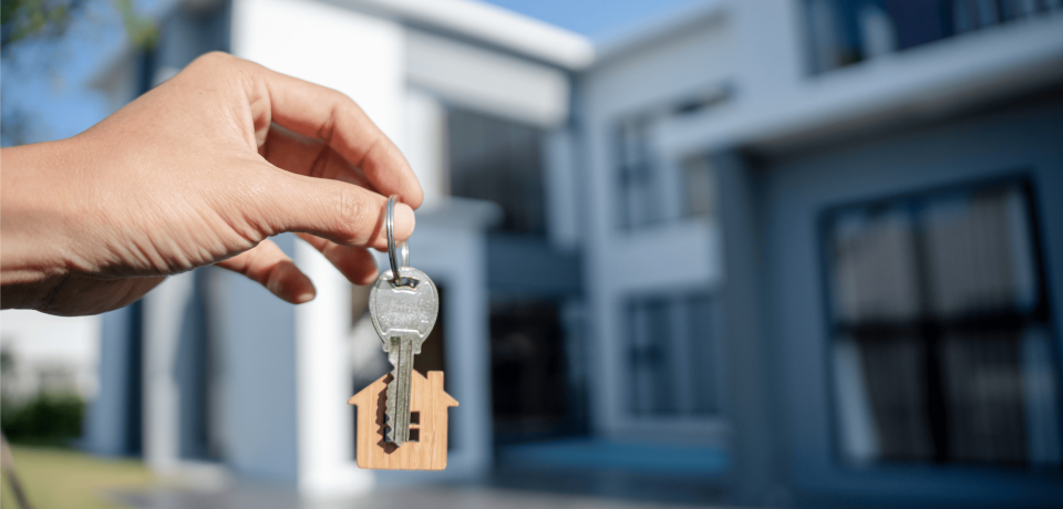 Keys with a house-shaped keychain in front of a modern property in Toowoomba, Queensland.