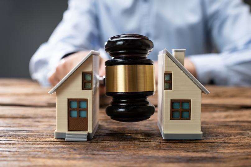 Property law legal dispute with miniature houses and gavel on wooden table.