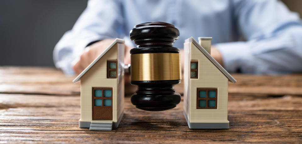 Property law legal dispute with miniature houses and gavel on wooden table.