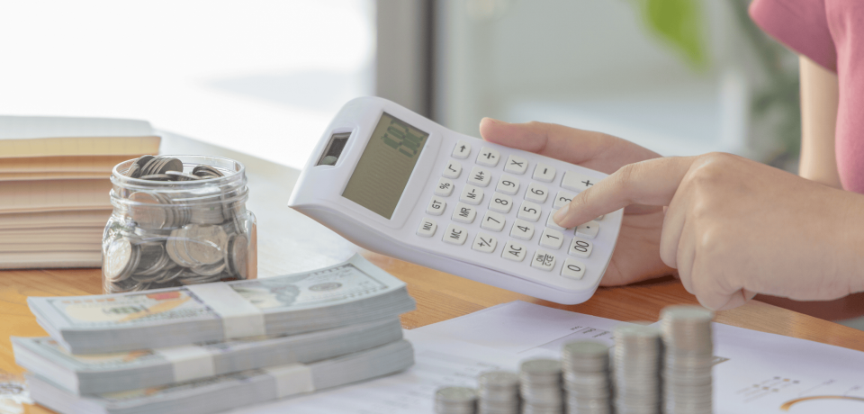 Coins in jar, calculator, and money stack on table representing financial planning, property, and legal services.