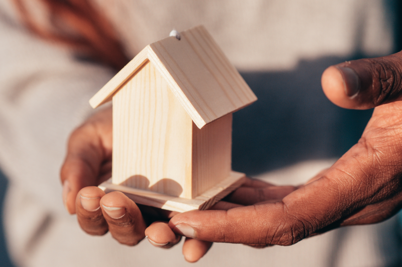 Small wooden house model held in hand, legal services for property law Queensland.