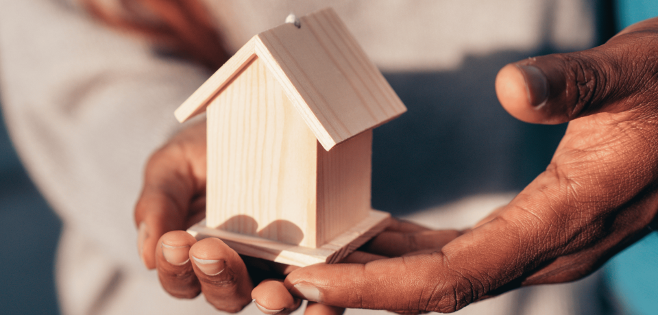 Small wooden house model held in hand, legal services for property law Queensland.