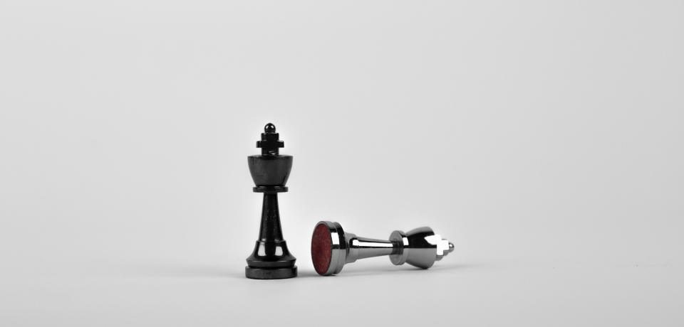 Black chess king and fallen king piece on grey background, representing strategic legal advice in property and civil disputes.