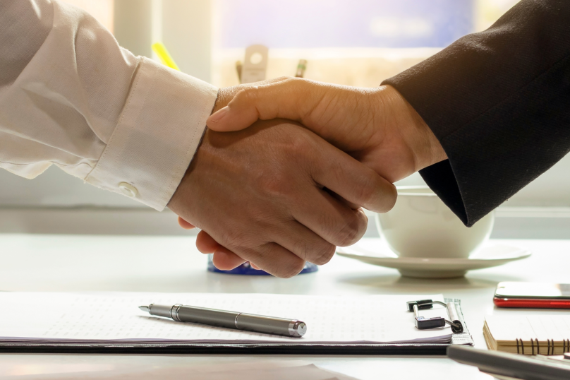 Handshake between professionals in a law firm meeting, representing legal agreement and partnership.