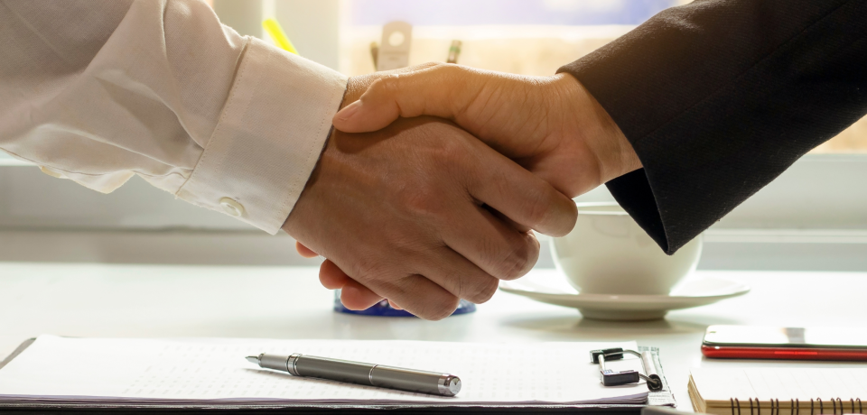 Handshake between professionals in a law firm meeting, representing legal agreement and partnership.